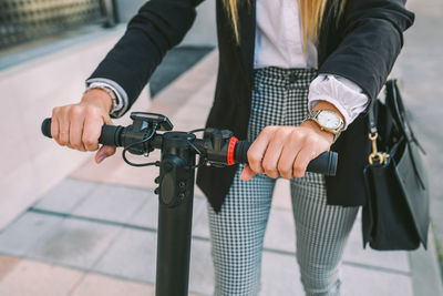 Midsection of man holding bicycle standing against blurred background