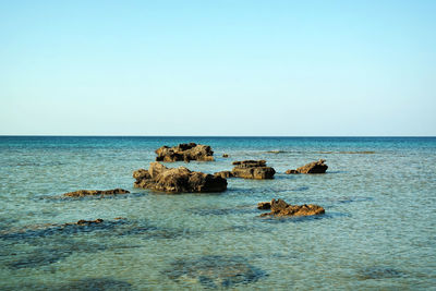 Rocks on sea against clear sky