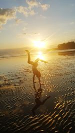 Woman on beach against sky during sunset