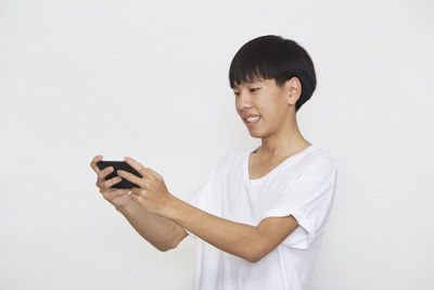 Young man using smart phone against white background