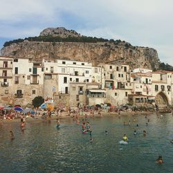 People on beach against buildings and sky in city