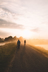 Rear view of people walking on road against sky