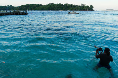 Man photographing while standing in sea