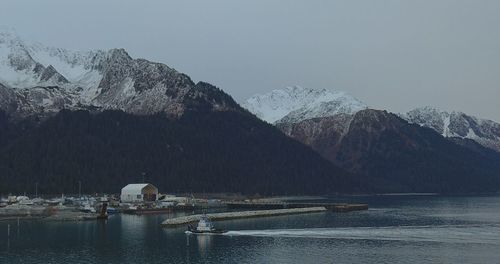 Scenic view of lake by snowcapped mountains against sky