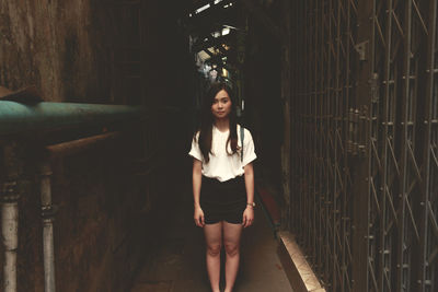 Portrait of young woman standing in alley