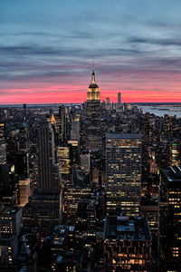 Illuminated buildings against sky during sunset in city