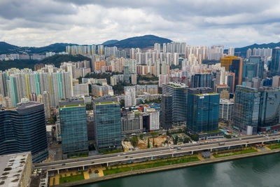 Aerial view of city by river and buildings against sky