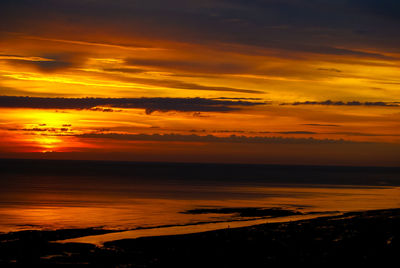 Scenic view of sea against dramatic sky during sunset