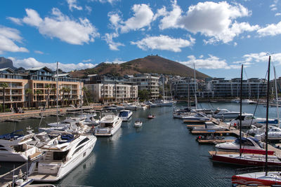 Boats moored at harbor by sea against sky
