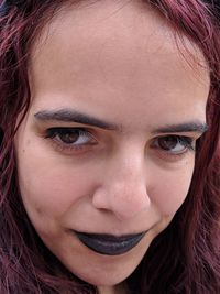 Close-up portrait of smiling young woman wearing black lipstick