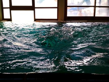 Swimming pool in sea seen through glass window