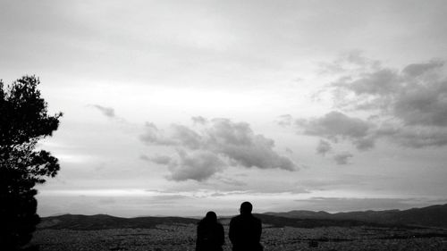 Rear view of silhouette people standing on landscape against sky