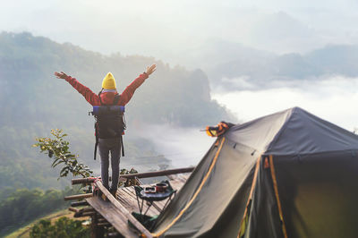 Rear view of woman with arms outstretched standing against landscape