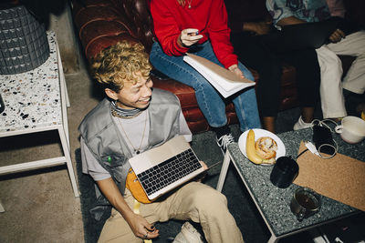 High angle view of smiling male entrepreneur with laptop while working in creative office