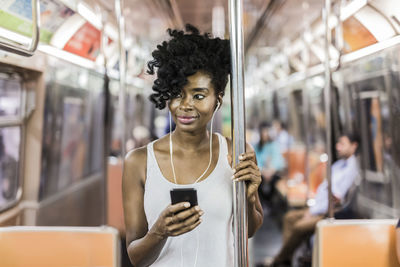 Usa, new york city, manhattan, portrait of relaxed woman with cell phone in underground train