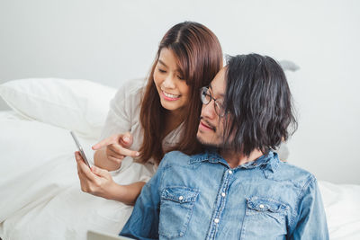 Young woman using mobile phone on bed