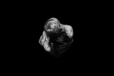 High angle view of brothers embracing over black background