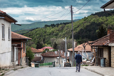 Rear view of people walking on street amidst houses