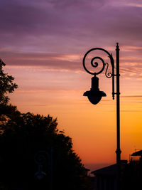 Silhouette street light against orange sky