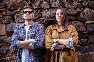 Portrait of young couple standing against wall