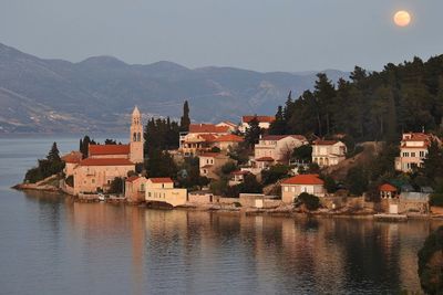 Houses by lake against sky in city