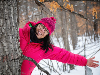 Portrait of smiling woman with pink face against trees during winter