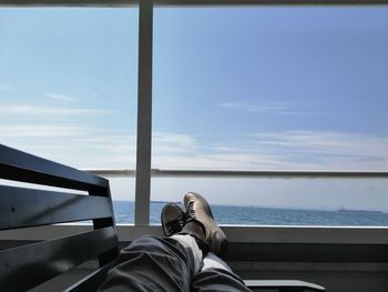Low section of man relaxing against sky