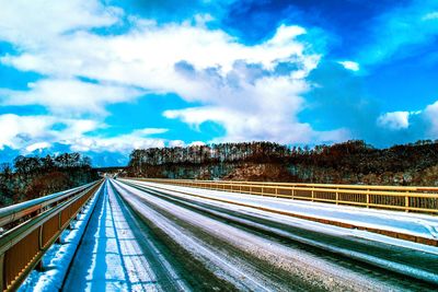 Road by trees against sky