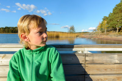 Portrait of boy looking at lake against sky