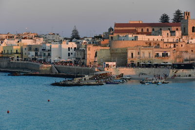 Sailboats in sea against buildings in city