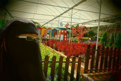 Rear view of woman standing in greenhouse