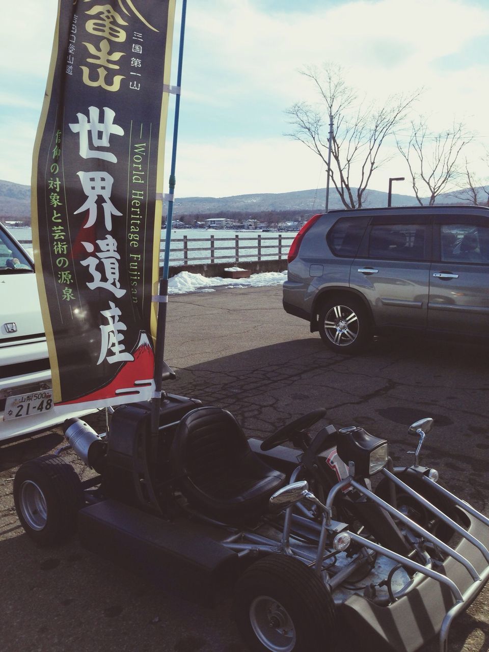 transportation, mode of transport, land vehicle, sky, car, text, stationary, cloud - sky, western script, parking, travel, communication, road, bicycle, cloud, no people, parked, outdoors, day, tree