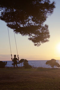 Silhouette people on beach against sky during sunset