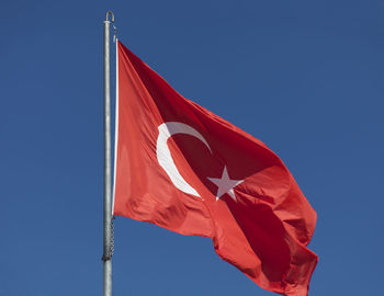 Low angle view of flag against blue sky