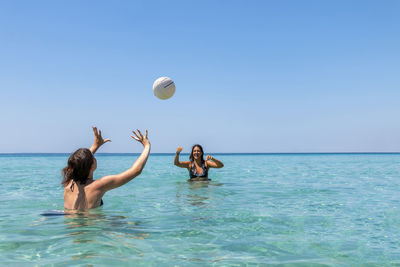 Happy teenagers playing volleyball in water at the vacation and fun