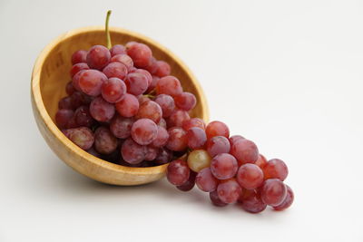 High angle view of grapes in bowl against white background