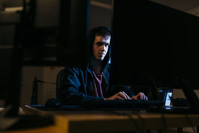 Young hacker working on computer while sitting at office