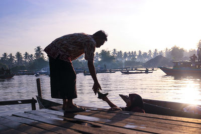 Man standing on pier over lake against sky