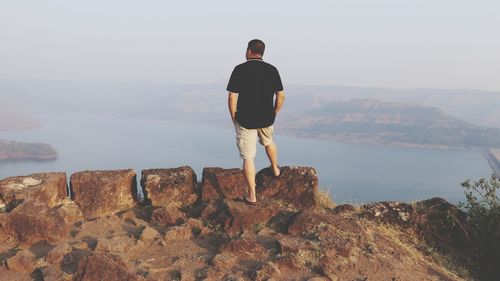 Rear view of man looking at mountains against sky