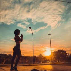 Side view of silhouette woman standing on street against sky