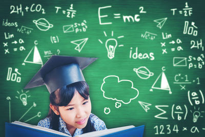 Teenage girl reading book against formulas on blackboard