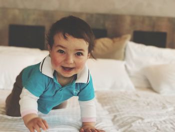 Portrait of smiling toddler on bed at home