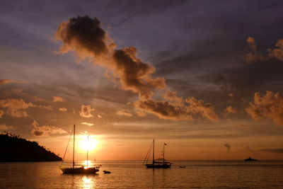 Silhouette sailboats in sea against sky during sunset