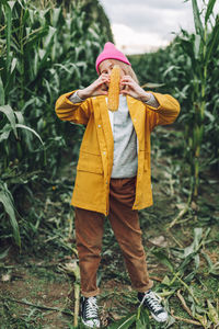 Funny little girl dressed in a yellow raincoat and a hot pink cap spoils and bites corn 