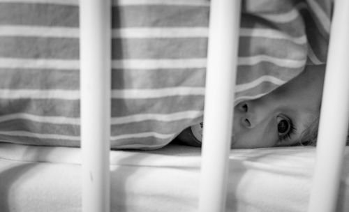 Close-up of boy lying in crib at home