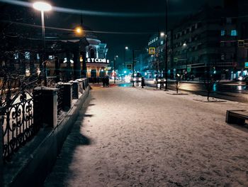 Illuminated street amidst buildings at night