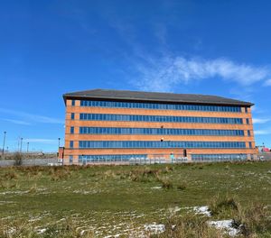 Low angle view of building on field against blue sky