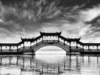 Bridge over river against cloudy sky