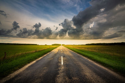 Road amidst field against sky