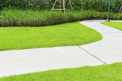 Grey concrete paving walkway on green grass lawn in a garden field